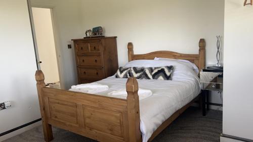 a bedroom with a wooden bed and a dresser at Immaculate 3-Bed Barn in Uttoxeter in Uttoxeter