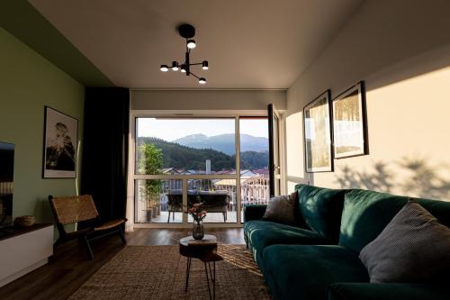 a living room with a green couch and a large window at Hedarom in Sinaia