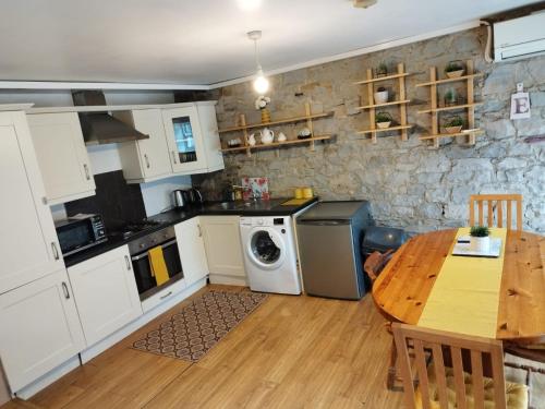 Grange cottages في Edenderry: مطبخ مع طاولة وموقد وغسالة
