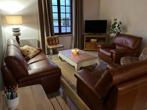 - un salon avec des canapés en cuir et une table basse dans l'établissement Gîte REVILLE 6/7 personnes, à 900 m de la mer, à Réville