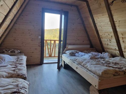 two beds in a room with a large window at Vila Suvo vrelo in Jahorina