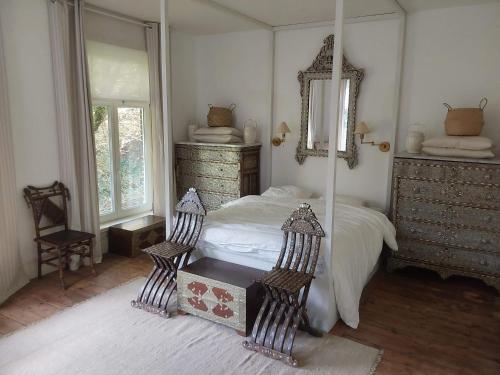 - une chambre avec un lit avec un miroir et deux chaises dans l'établissement Kasteel Sint-Flora, à Furnes