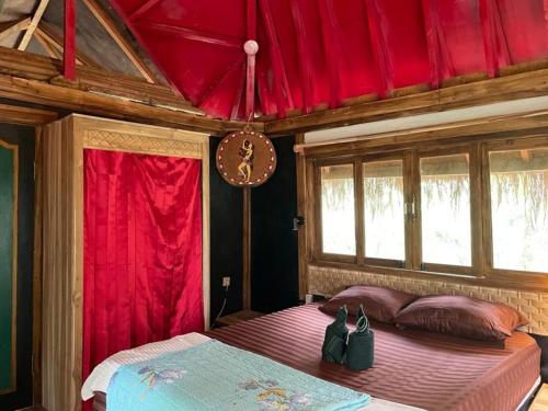 a bedroom with a large bed with red curtains at Satu Lingkung in Tetebatu