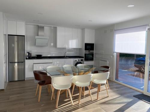 cocina con mesa de madera y sillas blancas en Villa Castro en Nuévalos