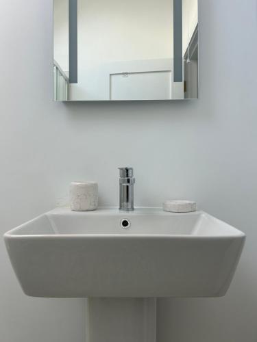 lavabo blanco en el baño con espejo en A Village Gem en Mullingar