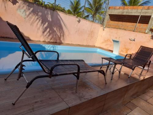 2 sedie sedute accanto alla piscina di Aconchego a Guarujá