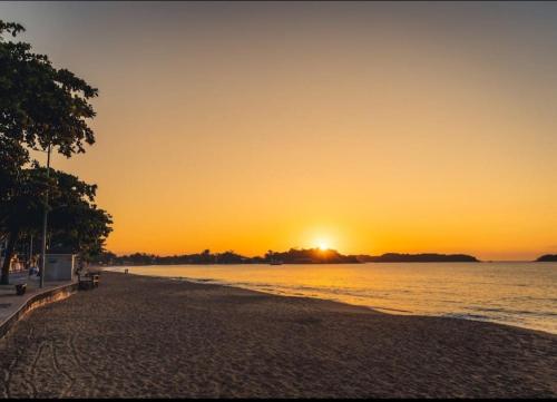a beach at sunset with the sun setting over the water at POUSADA AMAZONAS in Rio das Ostras