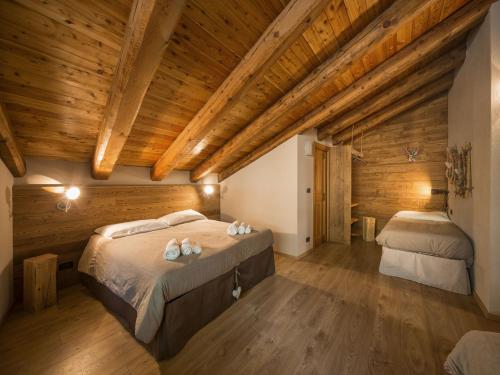 a bedroom with two beds and wooden ceilings at La Mizoùn de Marguerito - Appartamento Rododendro in Acceglio