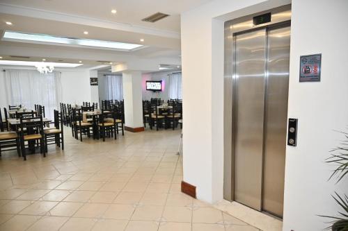 a dining room with tables and chairs and a elevator at Hotel Globo in Durrës