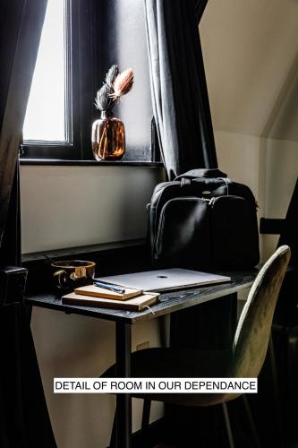 a desk with a laptop and a bag on it at Stella Suites Boutique Hotel in Goirle