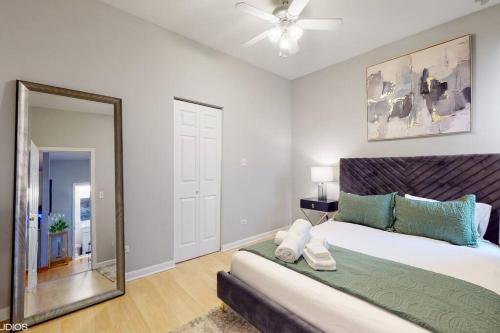a bedroom with a large bed and a mirror at Chic Green l Near Downtown & IL Medical District in Chicago