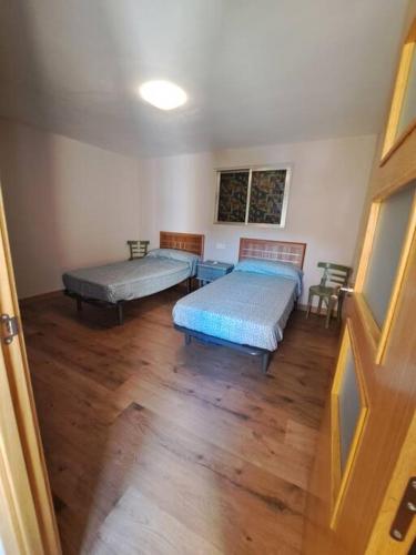 twee bedden in een kamer met houten vloeren bij Maravillosas vistas 