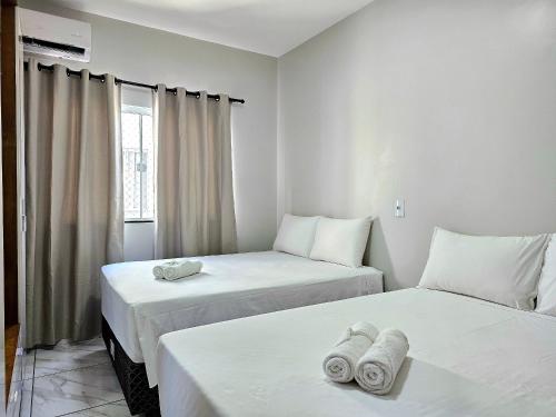 twee bedden in een kamer met witte muren en een raam bij Lindo APT, prox Paraguai com Churrasqueira in Foz do Iguaçu