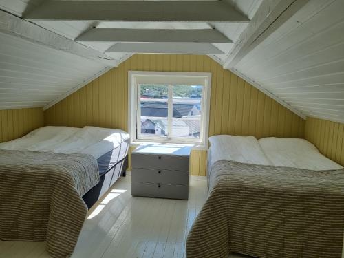 two beds in a room with a window at Loftsleilighet midt i sentrum in Skjervøy