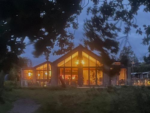 a house with large glass windows at night at Luksus hus i 1st række, all-incl top komfort med SPA og skov in Strøby