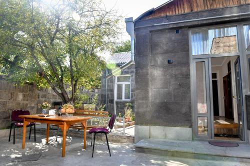 un patio con mesa de madera y sillas en Guest House David's B&B, en Gyumri