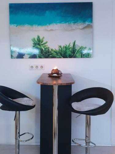 a table with two black chairs and a painting at FeWo Goslar Harz in Goslar