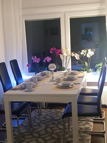 a dining room table with blue chairs and flowers at FeWo Goslar Harz in Goslar