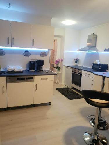 a kitchen with white cabinets and a stove and a stool at FeWo Goslar Harz in Goslar