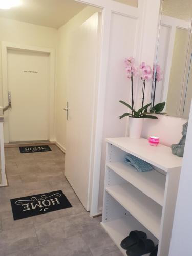 a room with a white dresser with a mirror and pink flowers at FeWo Goslar Harz in Goslar