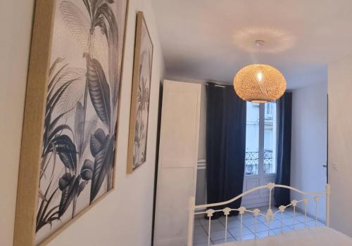 een kamer met schilderijen aan de muur en een kroonluchter bij Authentique Maison Sétoise 2 chambres Patio Proximité Parking Climatisation in Sète