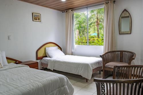 1 Schlafzimmer mit 2 Betten, einem Fenster und einem Stuhl in der Unterkunft Tropical Bliss Pool Wi-Fi BBQ Near Quepos Manuel Antonio in Quepos