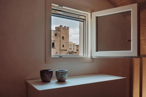 deux vases assis sur une étagère sous une fenêtre dans l'établissement Il Maniero, à Grottaglie