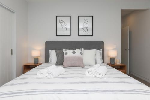 a bedroom with a large white bed with two lamps at Serenity on Sophia in Rotorua