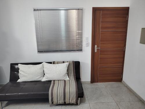 Sofá de cuero negro con 2 almohadas y puerta de madera en María Montaña - Departamento en San Juan en San Juan