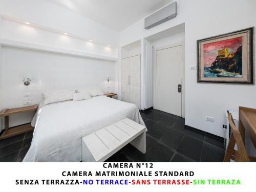 a bedroom with a white bed and a painting on the wall at I Tibei Guesthouse Affittacamere in Monterosso al Mare