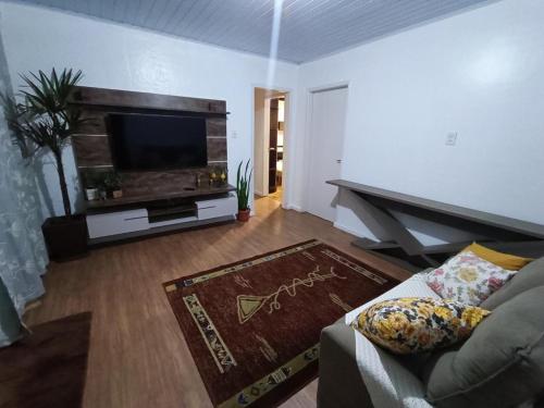 un soggiorno con divano e TV a schermo piatto di Casa com piscina em Torres/RS a Torres