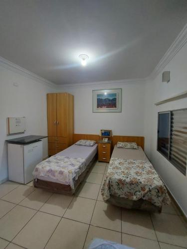 a bedroom with two beds and a kitchen with a tv at Hotel Mooca in Sao Paulo