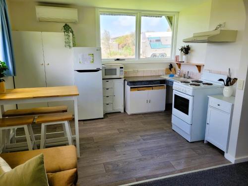 cocina con electrodomésticos blancos y suelo de madera en High View Family Cottages, en Warrnambool