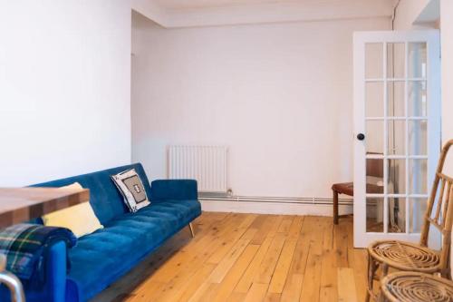 a living room with a blue couch and a wooden floor at Peaceful 1BD Flat with Private Garden Brighton! in Brighton & Hove