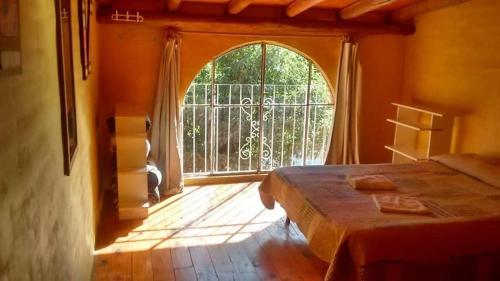 een slaapkamer met een bed en een groot raam bij Cabañas la Casa del Tata in Potrero de los Funes