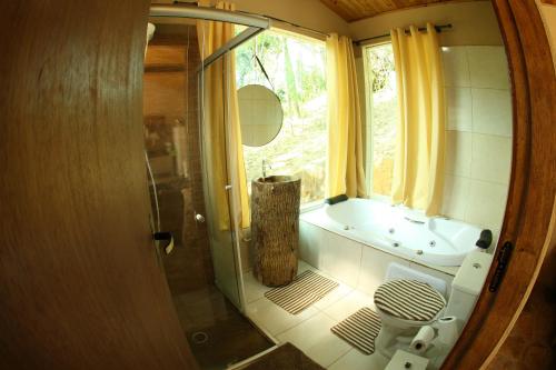 a bathroom with a shower and a toilet and a window at Cabana Refúgio da Mata in Juquitiba