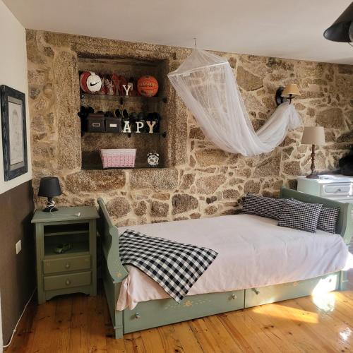 a bedroom with a bed and a stone wall at El Abuelo Angel in Ribadavia