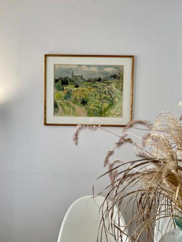 une image accrochée à un mur avec une plante dans l'établissement Le Beaugency Near Paris & Disneyland, à Champs-sur-Marne