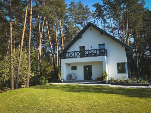 una casa bianca con un tetto nero nel bosco di Przylesie Dom na Roztoczu 
