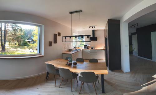 a kitchen and dining room with a wooden table and chairs at Przylesie Dom na Roztoczu 