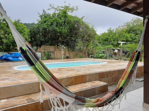 a hammock hanging in front of a swimming pool at Linda Casa Piscina Natureza in Florianópolis