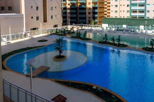 een groot zwembad met blauw water in een gebouw bij Apt encantador: piscina, academia, tela proteção in Taguatinga
