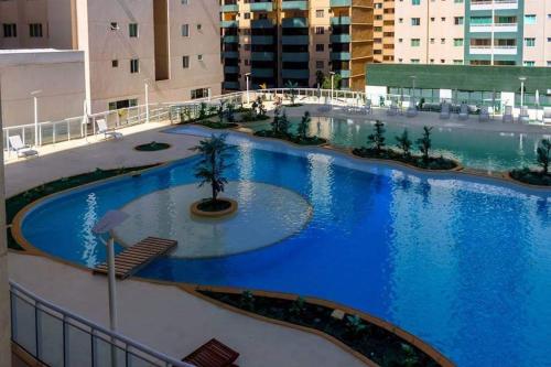 a large pool with blue water in a building at Apt encantador: piscina, academia, tela proteção in Taguatinga