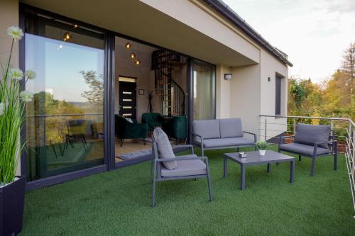 a patio with chairs and a table on the grass at Welcome House Eger in Eger