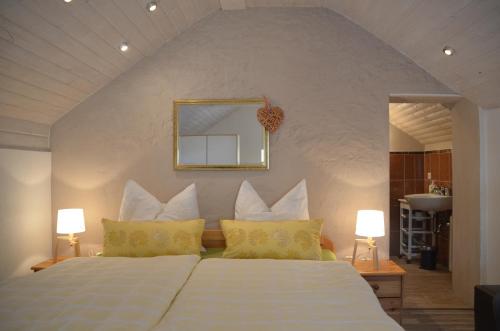 ein Schlafzimmer mit einem weißen Bett mit gelben Kissen und einem Spiegel in der Unterkunft Ferienwohnung Stübchen in Salmtal