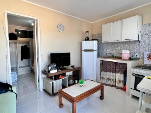 una pequeña cocina con nevera blanca y mesa en Quitieenete Arraial do Cabo, en Arraial do Cabo