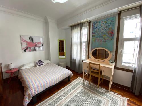 a bedroom with a bed and a desk and windows at Habitación Céntrica in A Coruña