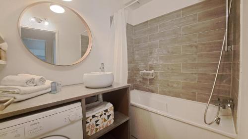 een badkamer met een wastafel, een spiegel en een bad bij Appartement de charme au coeur du Vieux Tours in Tours