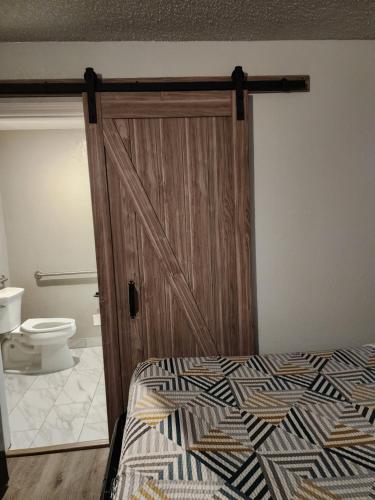 a bedroom with a wooden door with a bed and a toilet at Studio 6 Sacramento, CA Natomas in Sacramento