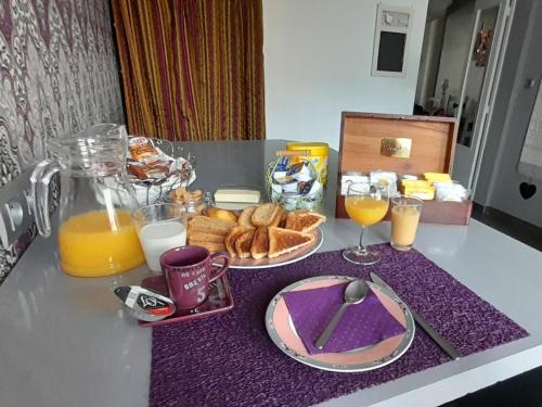 een tafel met een ontbijt van sinaasappelsap en brood bij Home Sweet Home in Le Mans